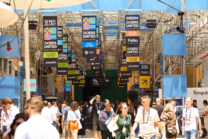 The Doers United expo boulevard under a canopy of partner banners, packed with attendees