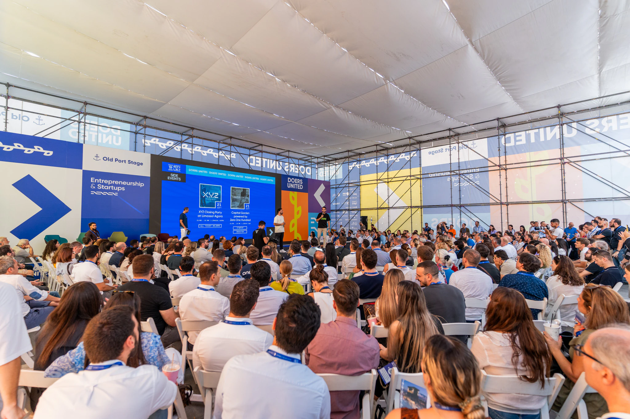 A packed Old Port Stage tent at Reflect Festival, the audience facing a Doers United screen