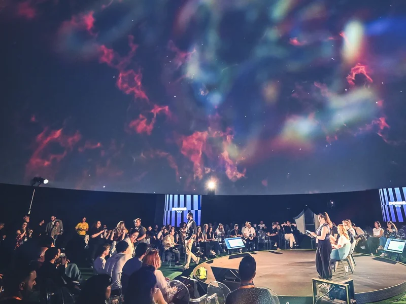 A pitch session in the dome, the audience circling the stage beneath a projected nebula